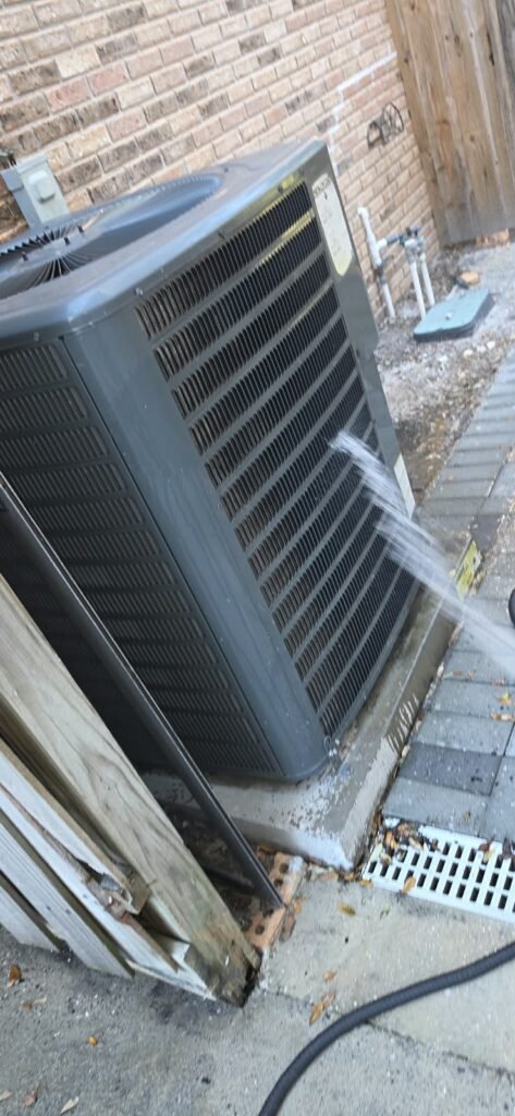 Hose Spraying on HVAC Unit Near Brick Wall, Tampa, FL 33612 Hose spraying water on HVAC unit near brick wall in Tampa, FL 33612