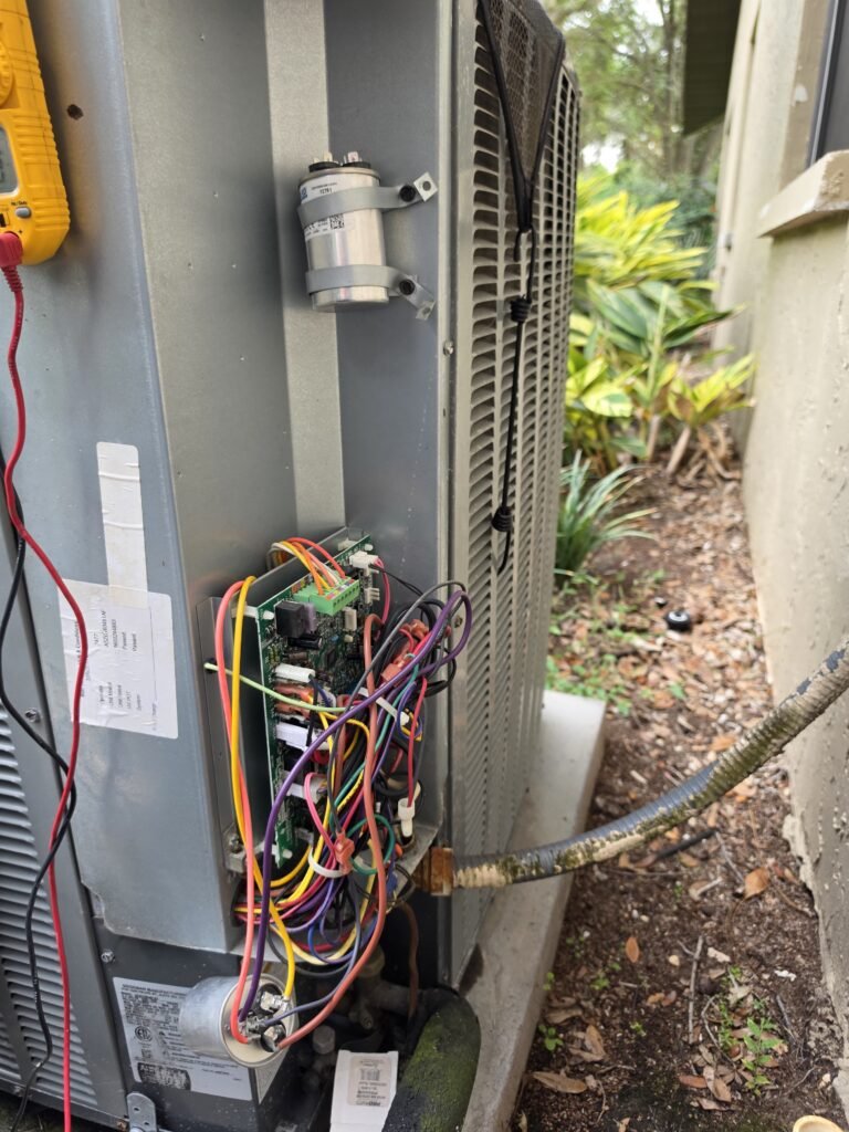 An outdoor AC unit opened up with a new capacitor mounted in Tampa, FL 33624.
