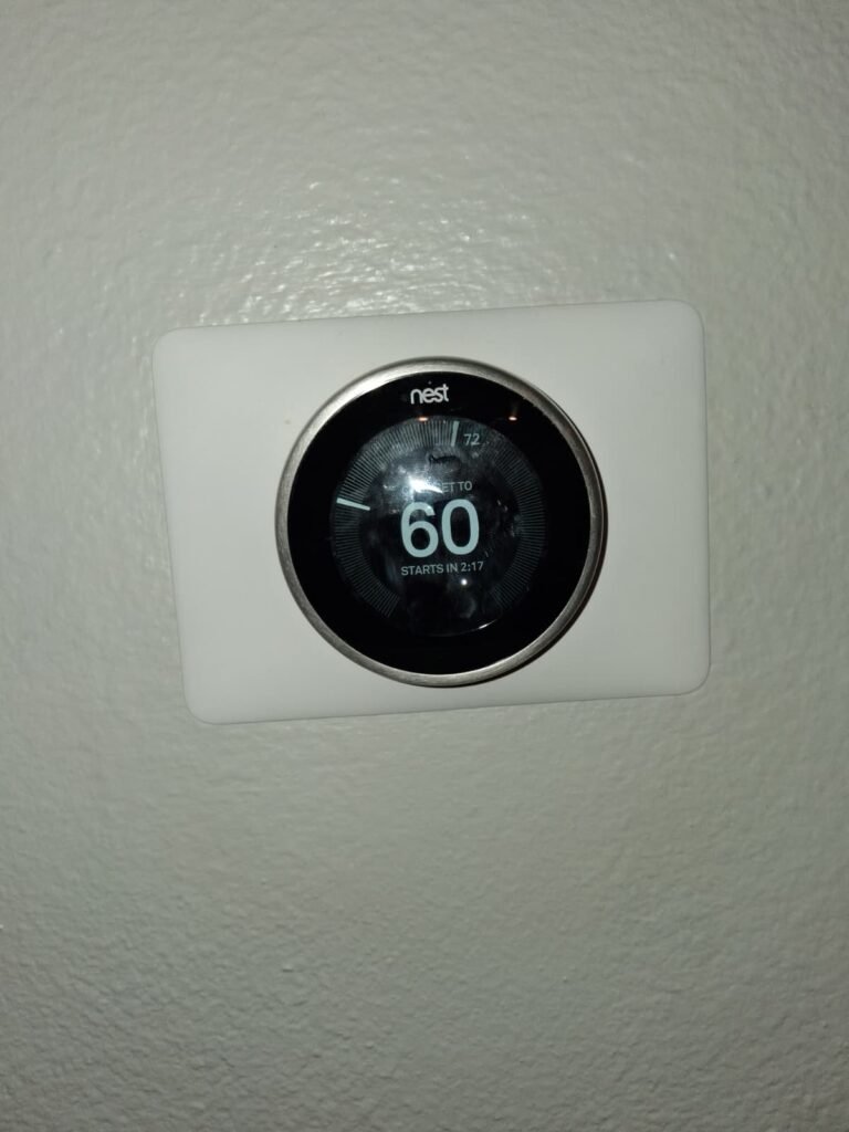 A Nest thermostat on a white wall plate in Tampa, FL 33602.