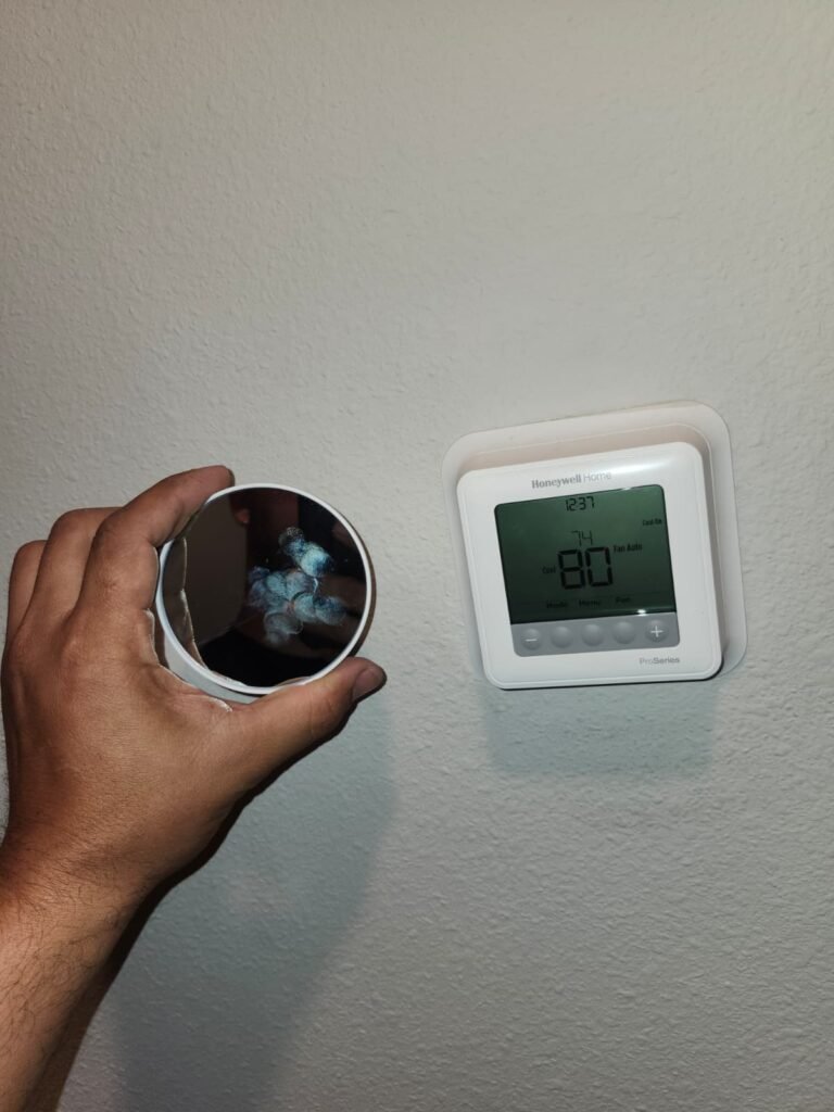 Hand holding object near installed thermostat in Tampa, FL 33619
