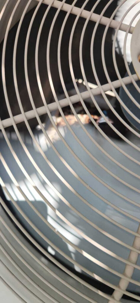 a close-up of an air conditioning unit's fan blades showing potential maintenance or inspection being performed by a technician