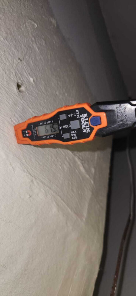a digital thermometer measuring temperature on a wall or surface indicating a reading of sixty one degrees fahrenheit