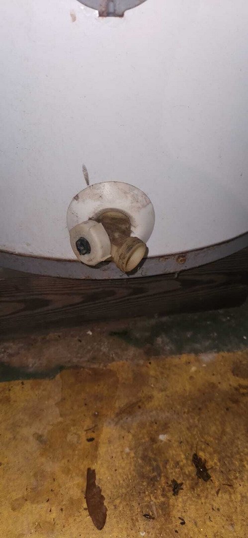 a plumbing service inspecting or repairing a water heater valve with visible wear and dirt around the base of the unit