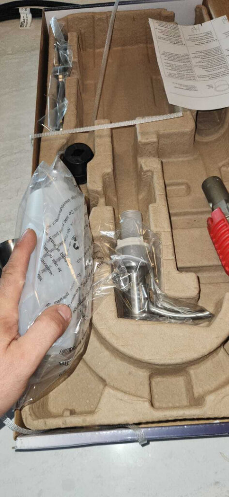assembled plumbing components inside a cardboard box with instructions and protective packaging materials visible
