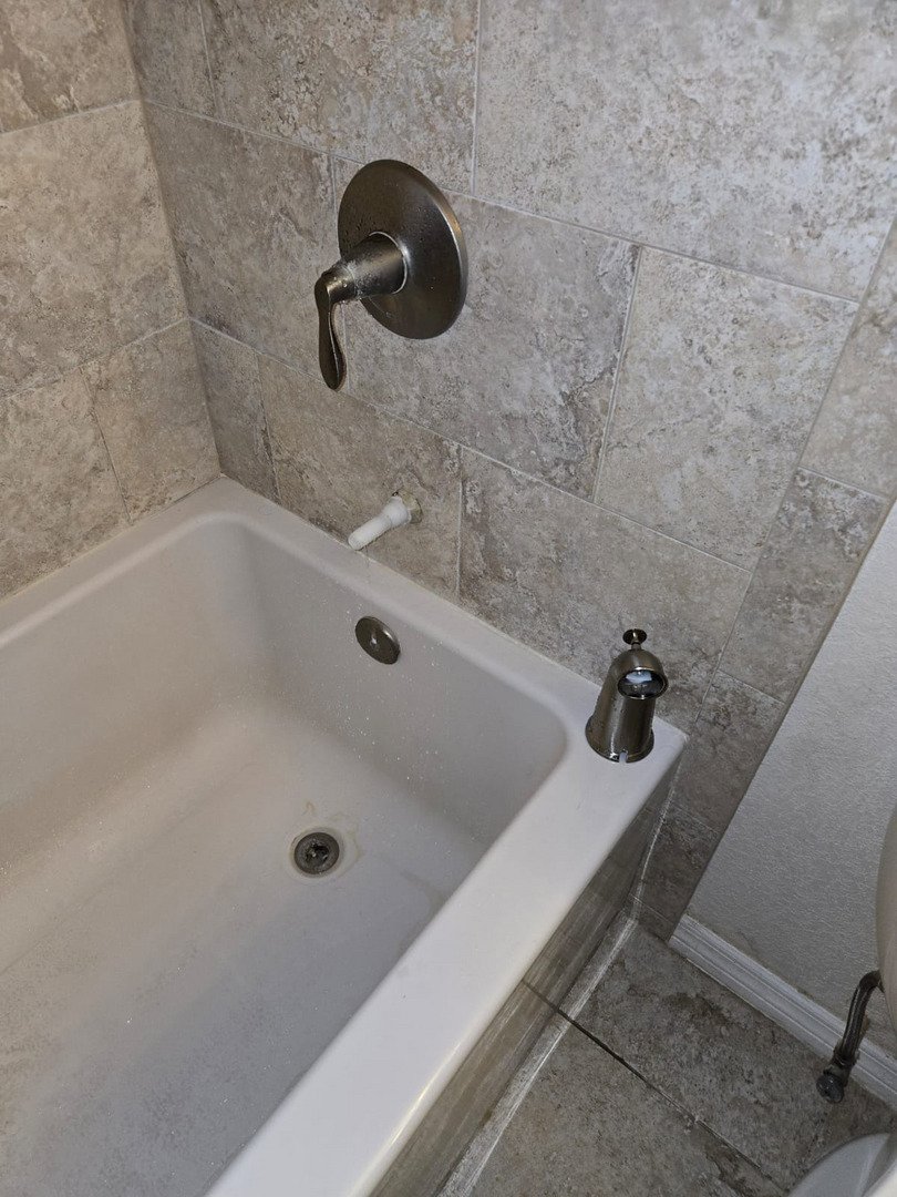 bathroom plumbing installation of a tub faucet in a tiled shower area with visible plumbing details