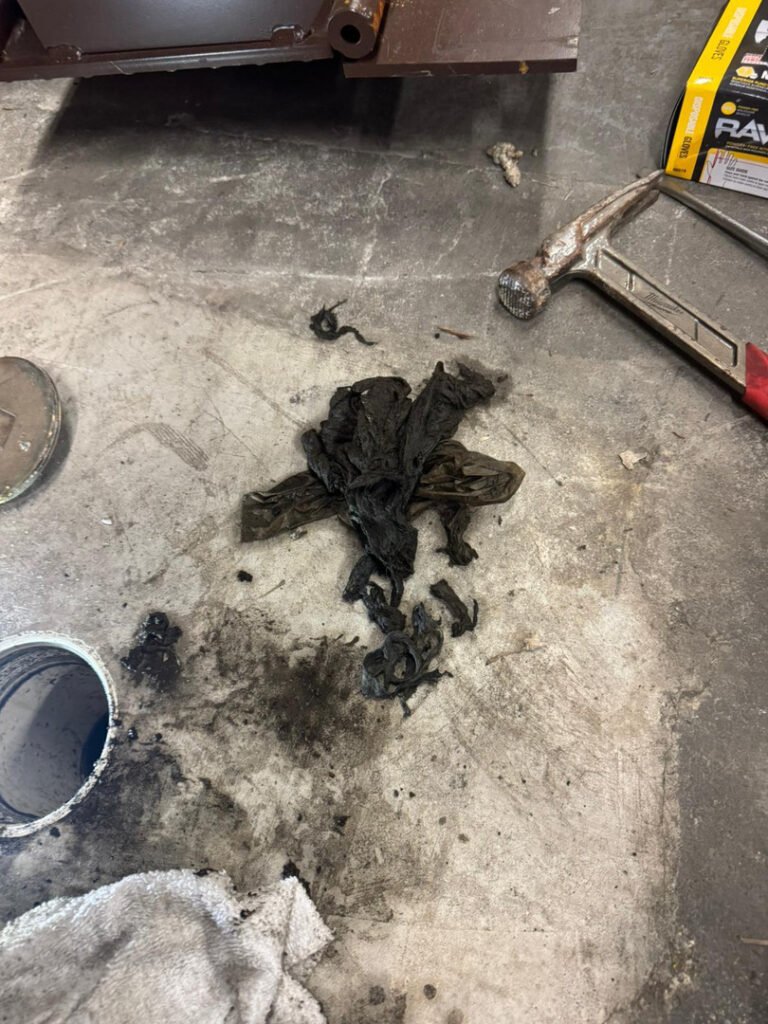 black debris and used materials on a concrete surface possibly from plumbing maintenance or repair work