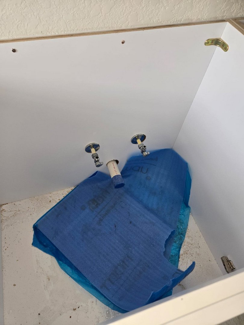 blue protective coverings are placed around plumbing fixtures in a cabinet awaiting installation or maintenance work