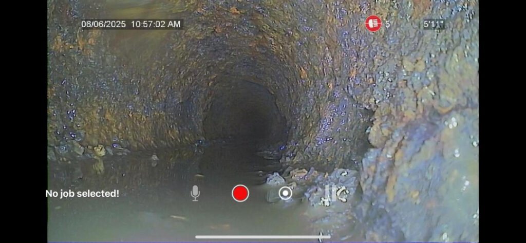 camera inspection of a sewer line showing debris and buildup in a dark tunnel indicating potential blockage issues