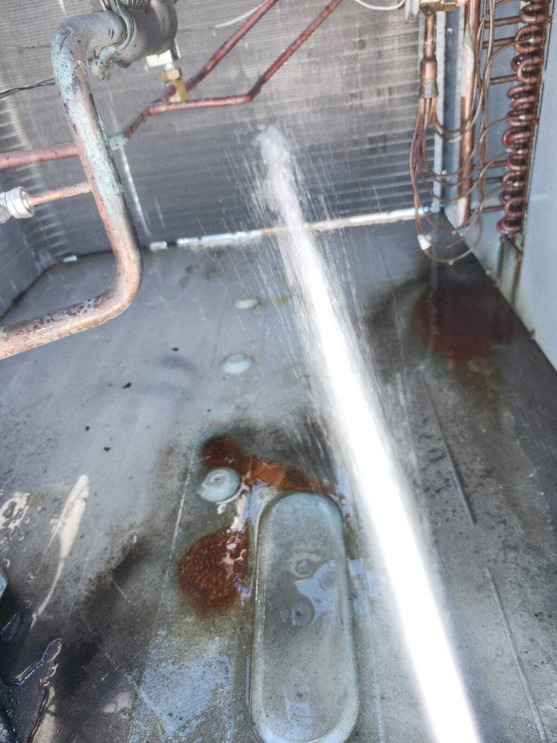 Cleaning A Metal Surface With Water Spray Showing Rust And Debris On The Floor