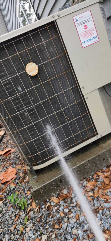 cleaning a residential air conditioning unit with a pressurized water spray on the fins and coils