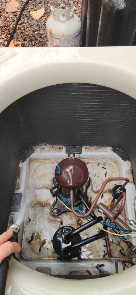 cleaning an air conditioning unit removing debris and dirt from the interior components applying water with a hose