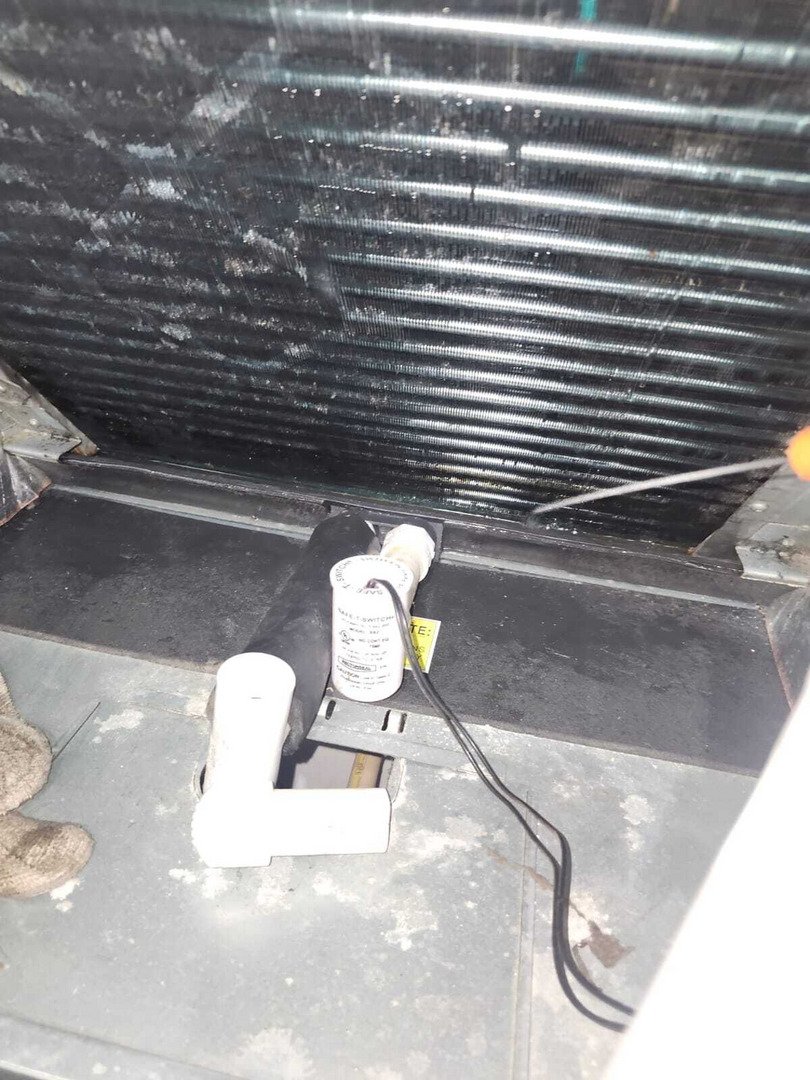 cleaning and inspecting an air conditioning unit's evaporator coil with visible dirt buildup and maintenance tools present