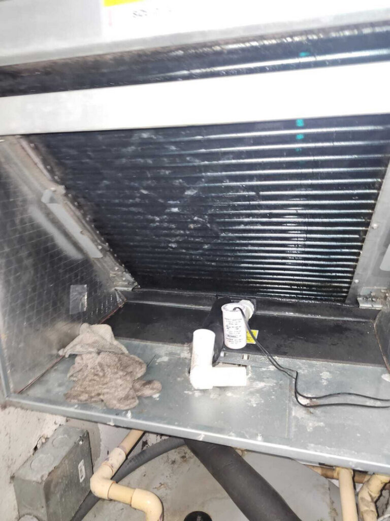 cleaning or inspecting an indoor air conditioning unit with a focus on coils and components near pipes and gloves