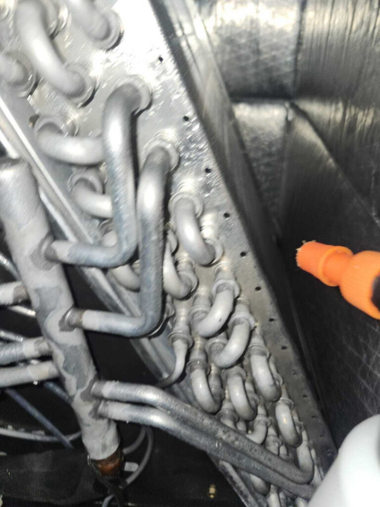 coils and tubing are being inspected or serviced in a heating or cooling system possibly for maintenance or repair