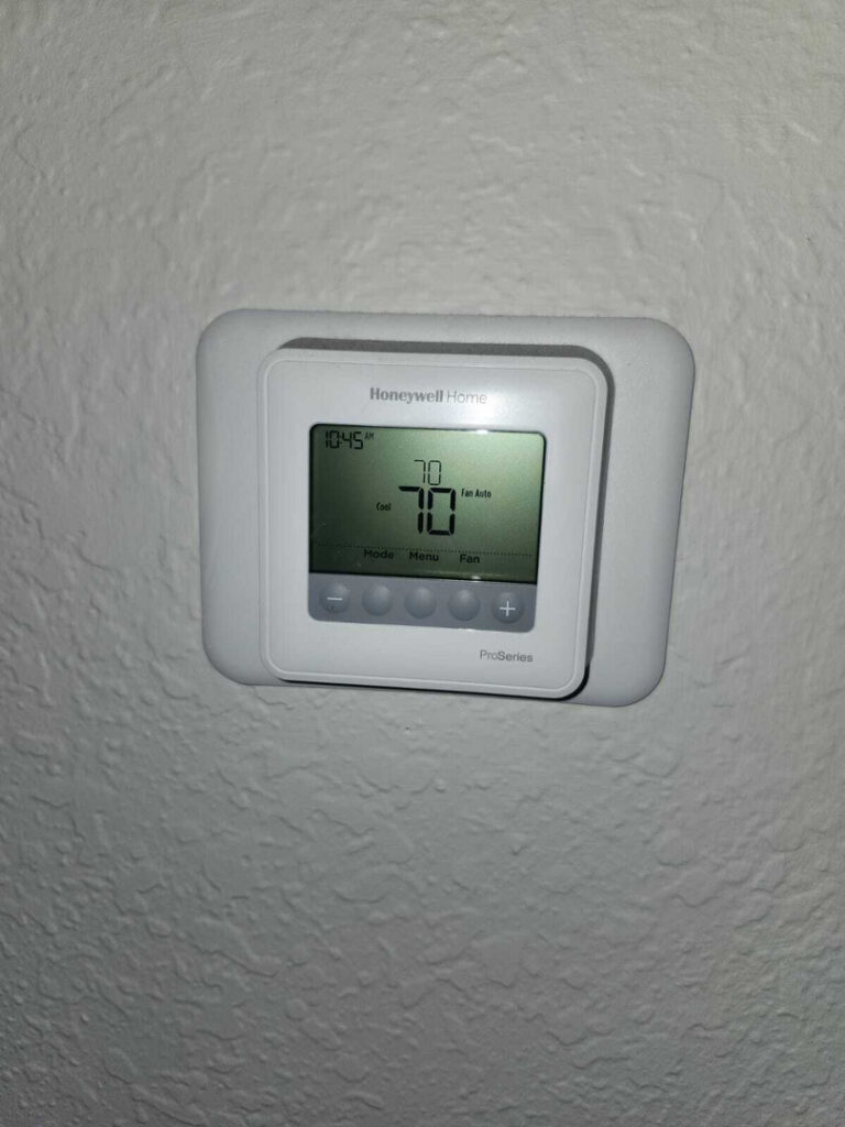 digital thermostat displaying current temperature settings and time mounted on a textured wall