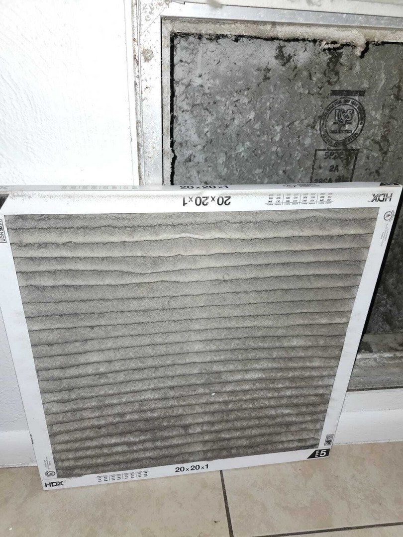 dirty air filter being replaced next to HVAC vent showing buildup of dust and debris in the system