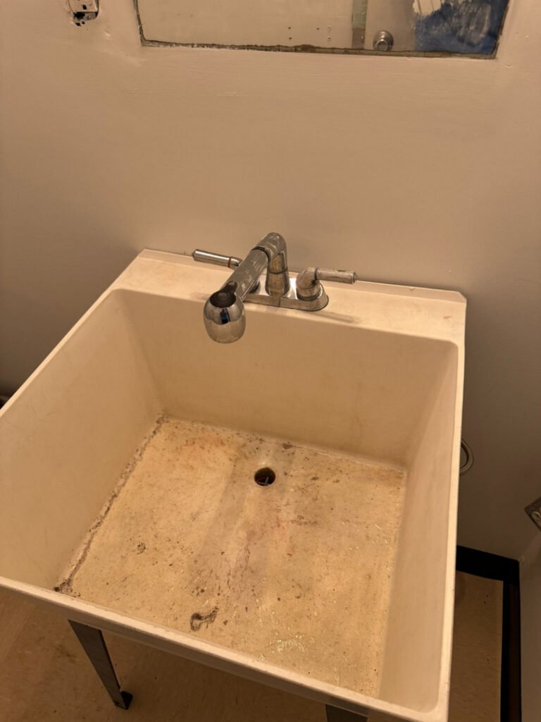 From one of our recent jobs: dirty utility sink with faucets some stains visible inside the basin likely needs cleaning or maintenance.
