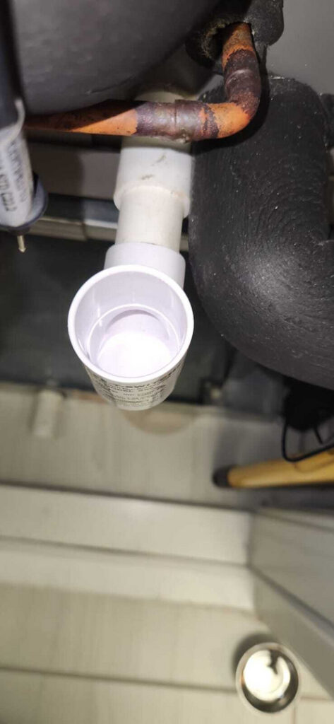 drain pan installed under a pipe likely for condensate collection in a heating or cooling system
