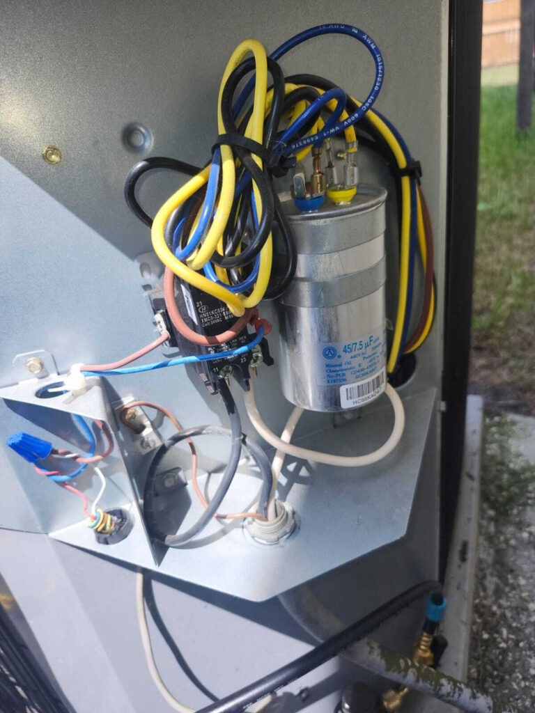 electrical connections on an outdoor cooling system with wires and a capacitor visible among other components
