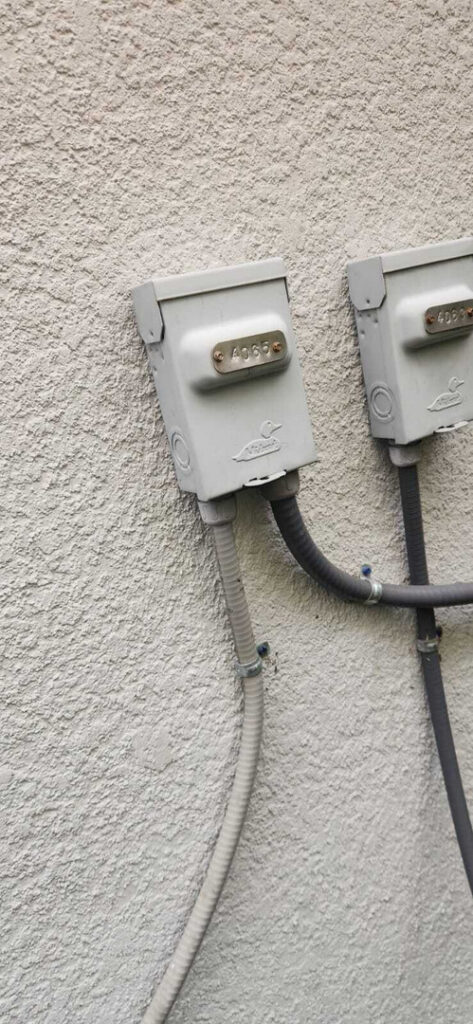 exposed electrical junction boxes attached to a textured wall with cables connected to them