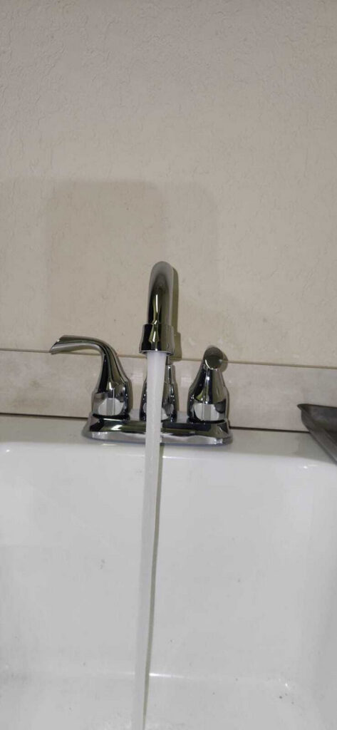 faucet dispensing water in a clean sink indicating plumbing services being provided with focus on plumbing fixtures