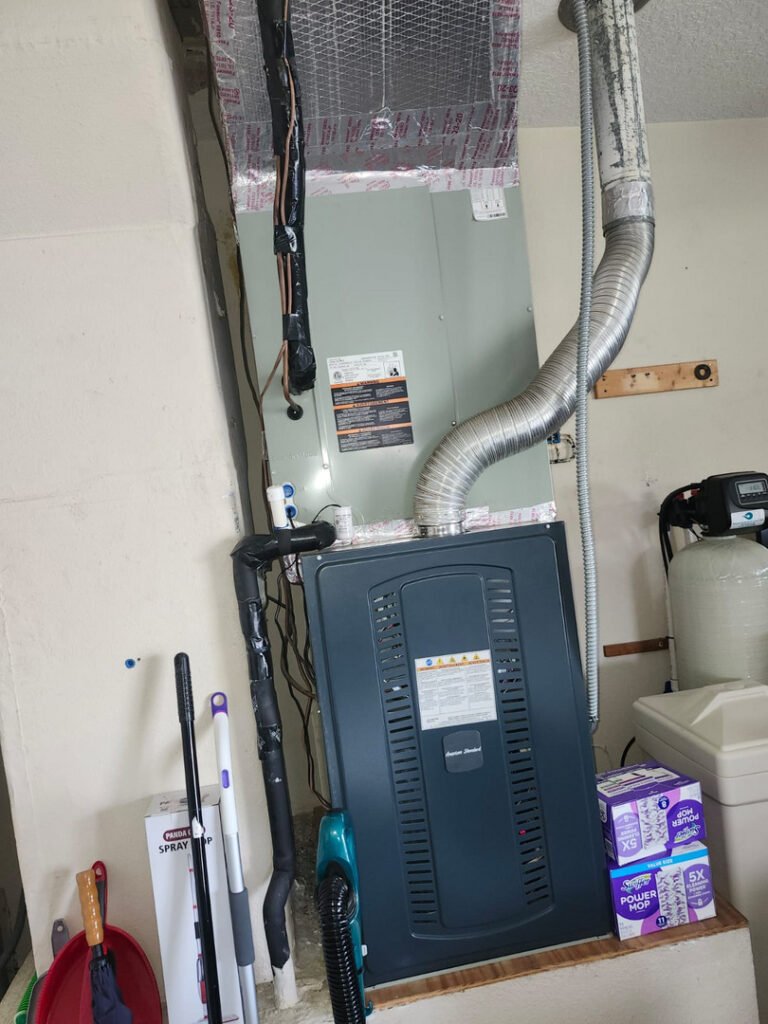 A gas furnace with its flue pipe and the coil cabinet above it, installed in a garage.