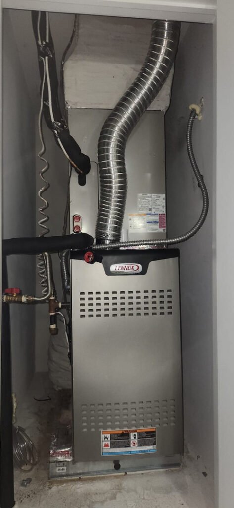 A Lennox gas furnace with its vent pipe and gas shutoff valve in a utility closet.