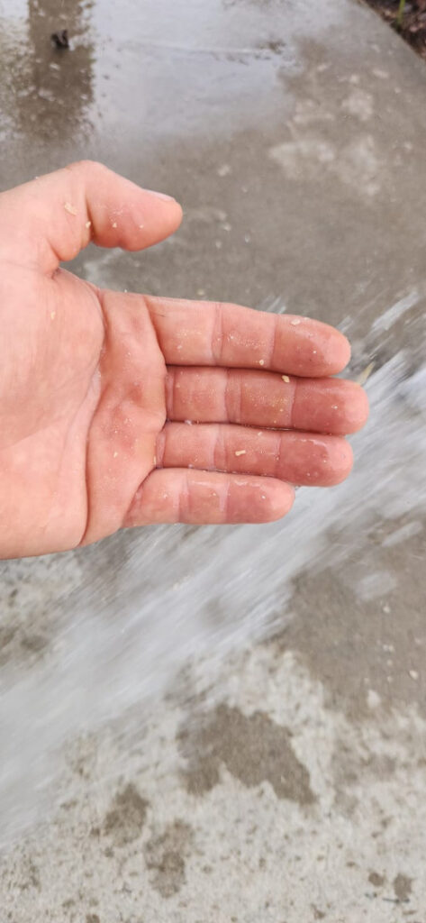 hand being held near flowing water on a concrete surface likely indicating a plumbing or water-related service