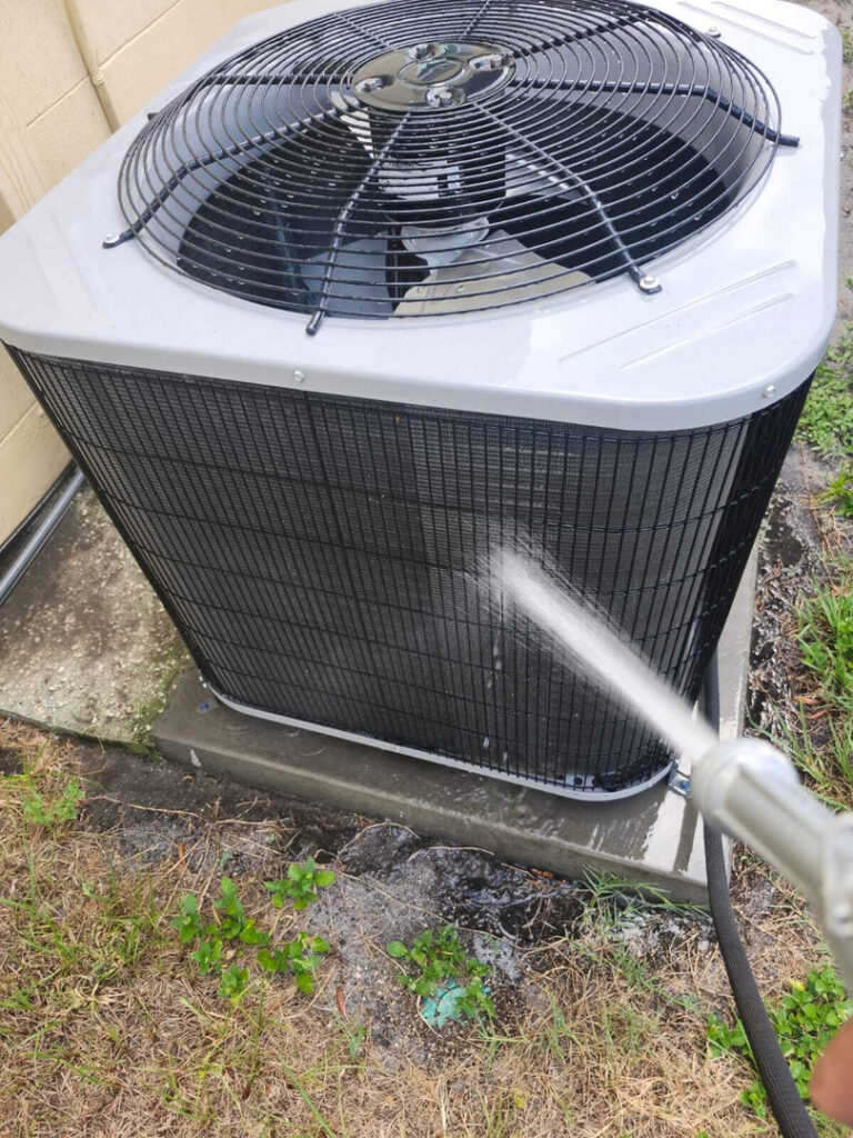 home therapist cooling heating and plumbing cleaning an air conditioning unit using a hose with water spray