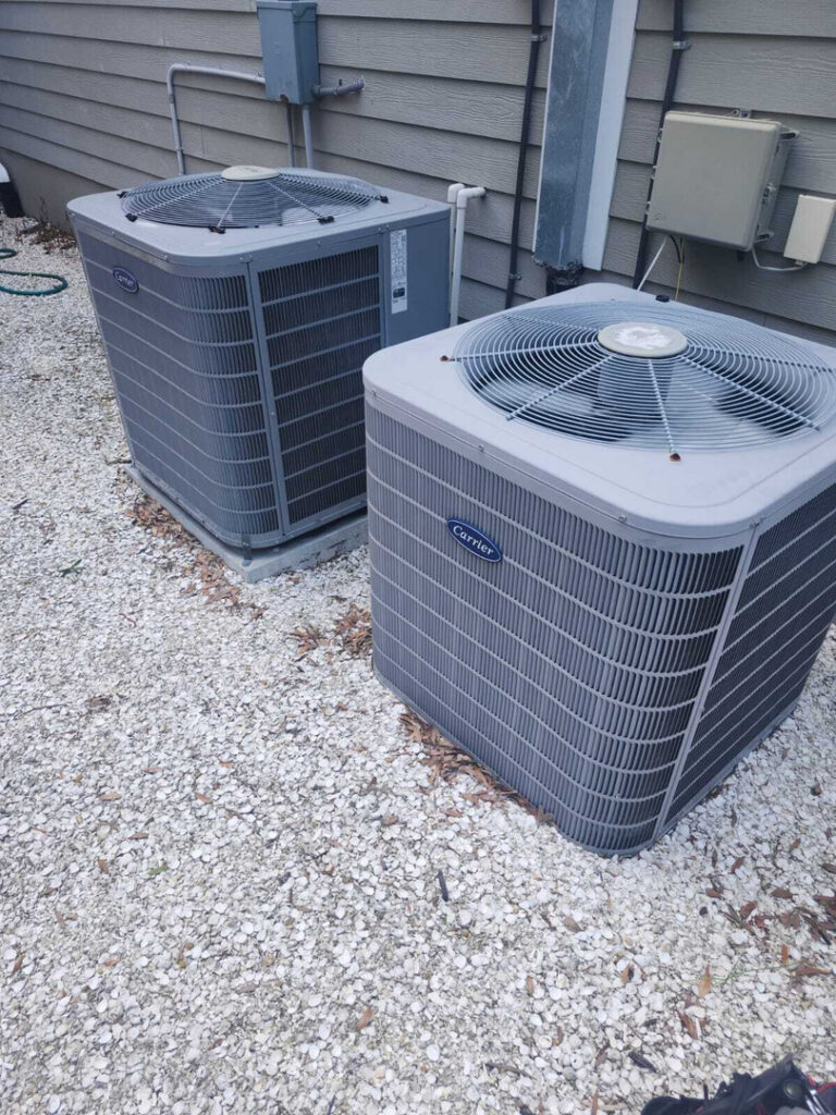 home therapist cooling heating and plumbing inspecting two outdoor air conditioning units positioned on gravel surface