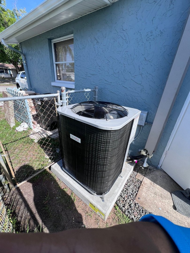 home therapist cooling heating and plumbing installing a new air conditioning unit next to a blue house