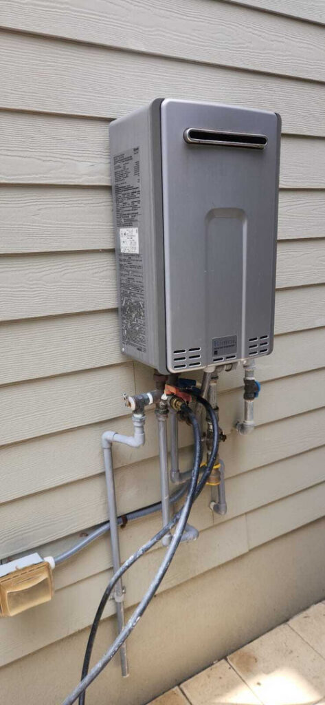 home therapist cooling heating and plumbing installing a silver tankless water heater mounted on a light colored wall