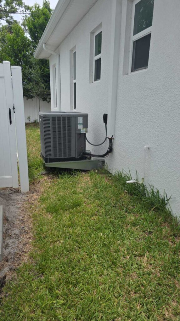 home therapist cooling heating and plumbing installing an air conditioning unit beside a white house with green grass