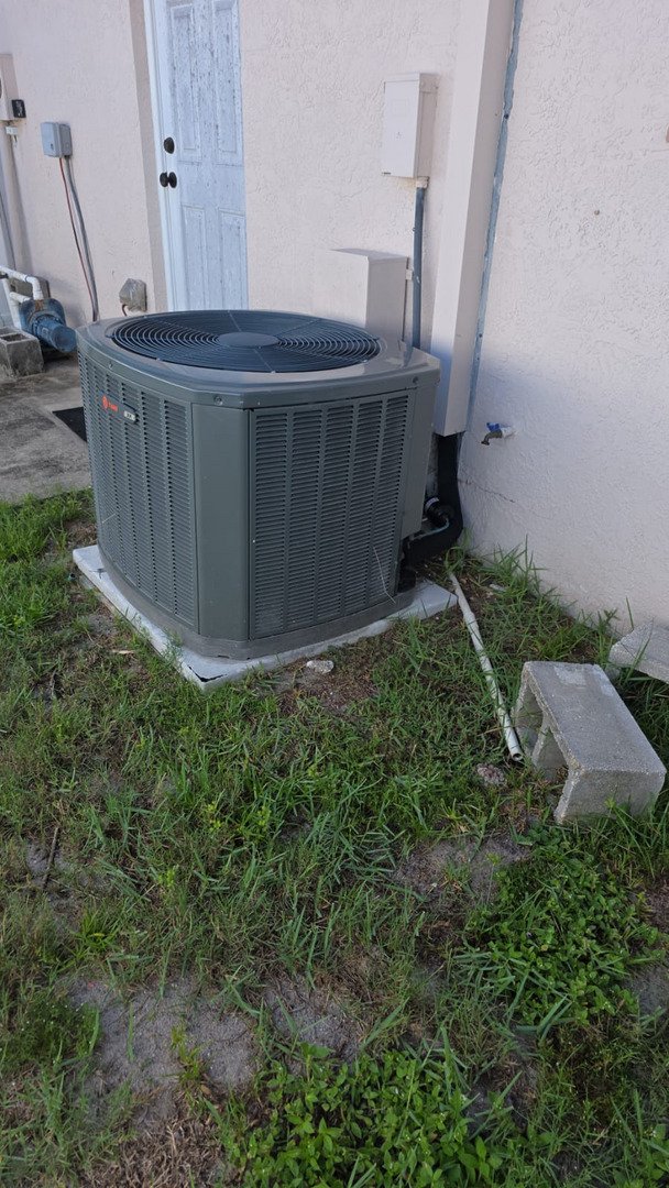 home therapist cooling heating and plumbing installing or servicing an air conditioning unit in a residential area