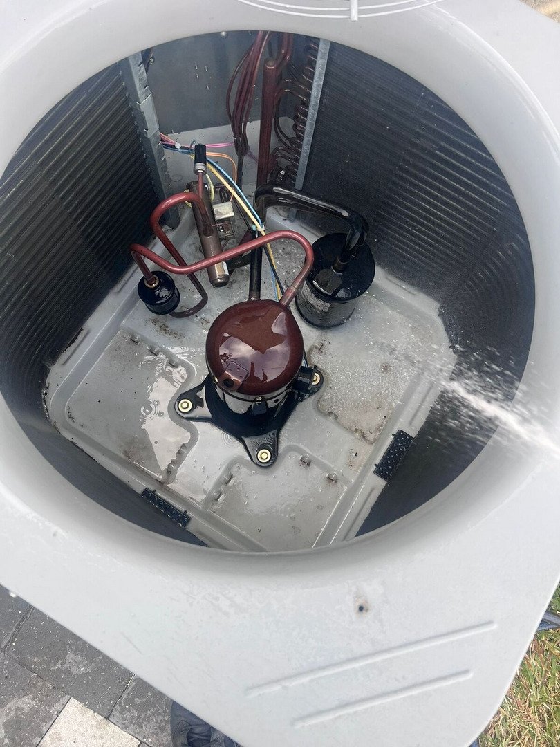 Home Therapist Cooling Heating And Plumbing Maintaining An Air Conditioning Unit With Visible Components And Water Accumulation Inside The Unit