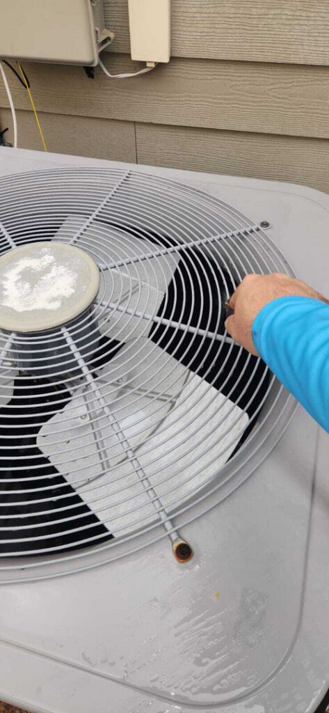 home therapist cooling heating and plumbing performing maintenance on an air conditioning unit using a cleaning solution and brush