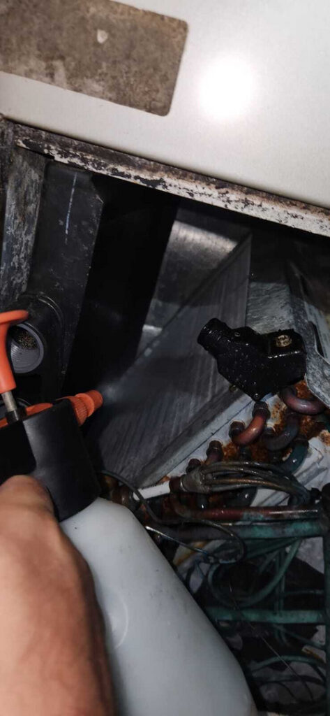 home therapist cooling heating and plumbing performing maintenance on hvac system using a spray tool on various components