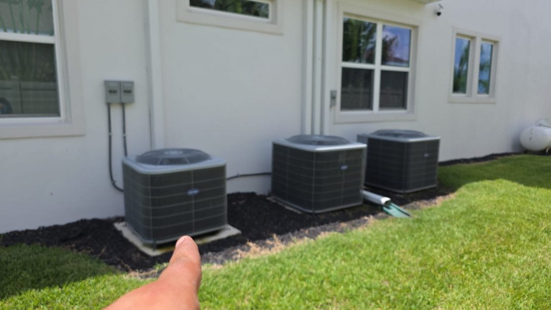 home therapist cooling heating and plumbing performing maintenance on three outdoor air conditioning units next to a house