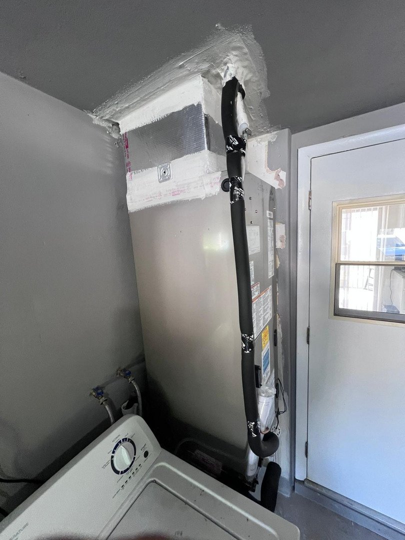 home therapist cooling heating and plumbing servicing a water heater with pipes and connections visible near a door and washer