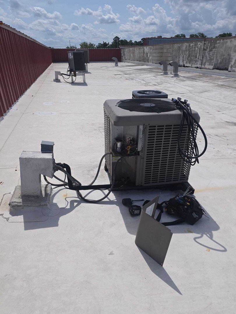 home therapist cooling heating and plumbing servicing an air conditioning unit on a flat roof with tools nearby