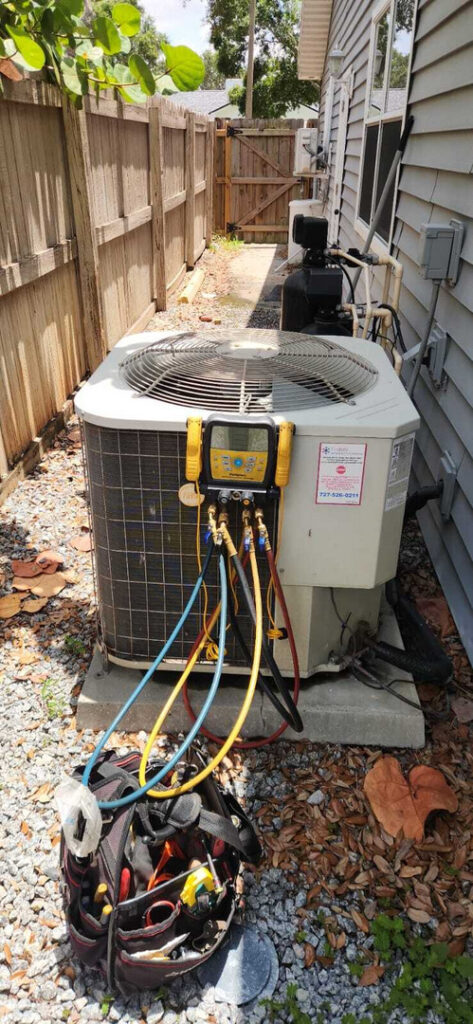 home therapist cooling heating and plumbing servicing an outdoor air conditioning unit with tools and gauges connected