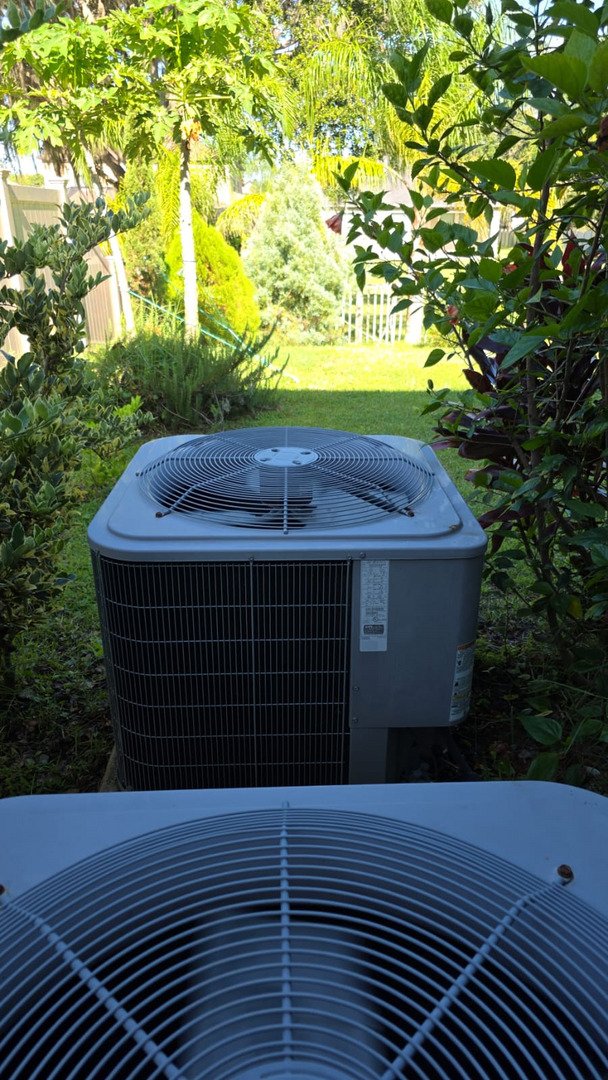 home therapist cooling heating and plumbing servicing outdoor air conditioning units surrounded by greenery and sunlight