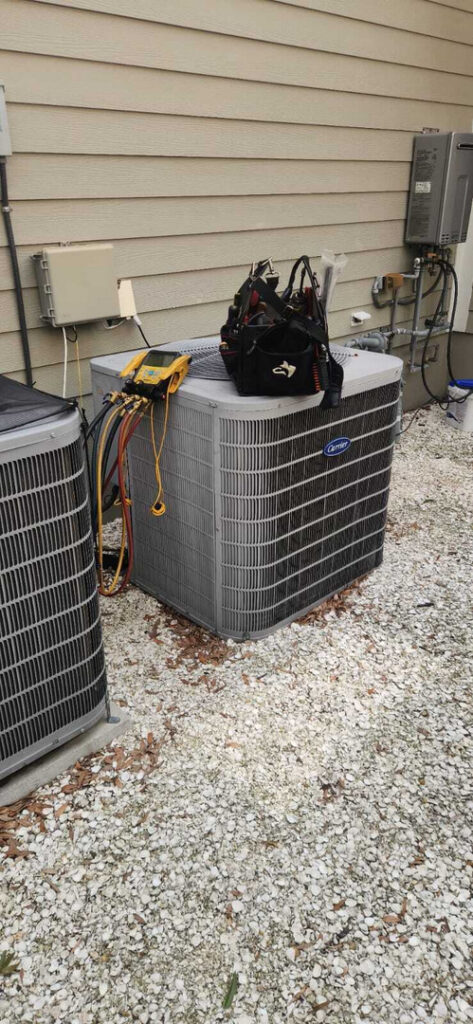 home therapist cooling heating and plumbing servicing two air conditioning units with tools and equipment on one unit