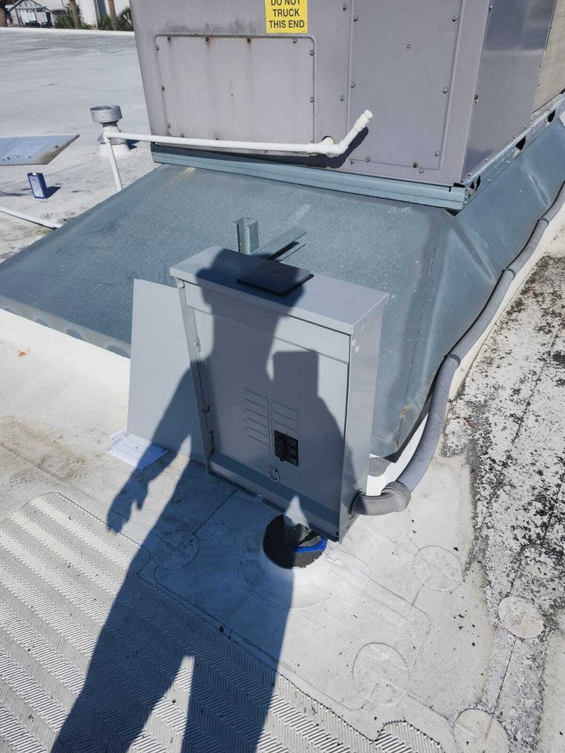 Installation Of A Rooftop Unit With Electrical Connections And Drainage Components Visible On A Flat Roof