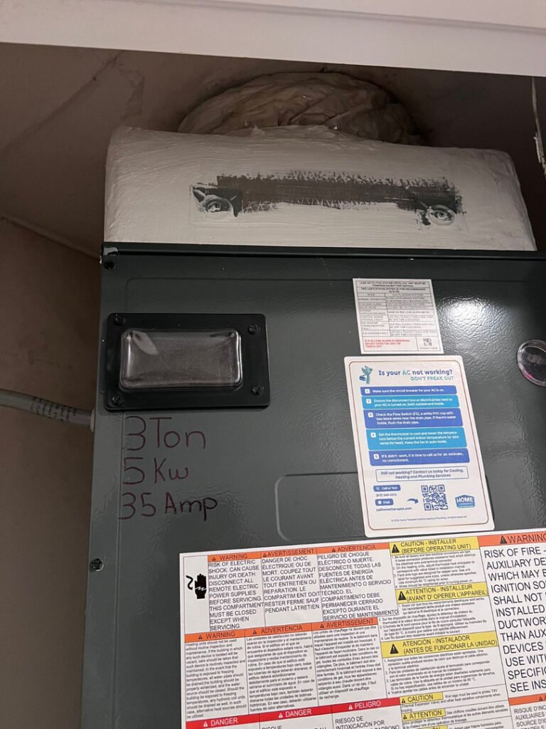 From one of our recent jobs: installation of a three ton air conditioning unit with warning labels and electrical specifications visible on the panel.