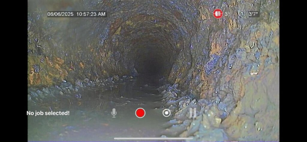 interior view of a sewer pipe showing buildup and debris likely for plumbing inspection purposes using camera technology