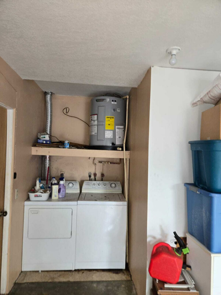 laundry area with a washer and dryer alongside a water heater on a shelf with cleaning supplies nearby