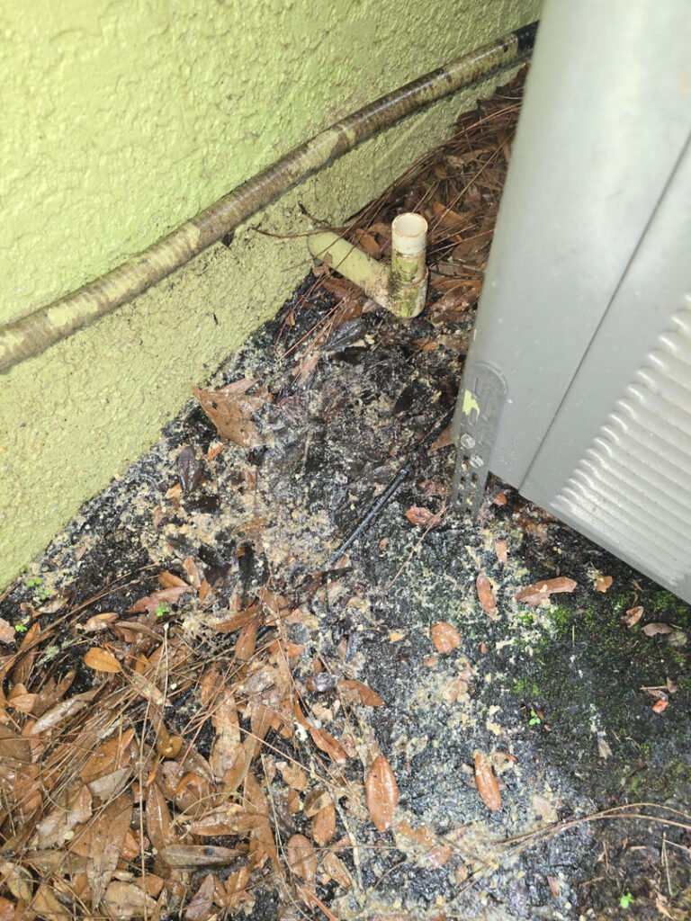 From one of our recent jobs: leaves and debris near an air conditioning unit indicating potential drainage issues or maintenance needs in the landscape area.