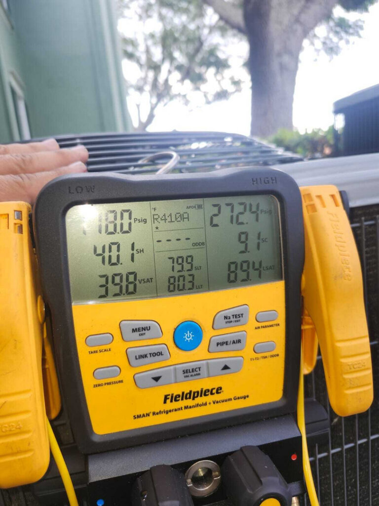 maintenance of air conditioning system using a refrigerant manifold gauge displaying pressure and temperature readings