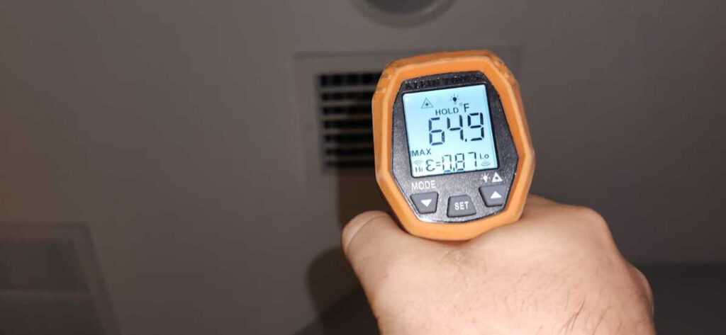 measuring air temperature with a digital thermometer near a vent in a residential setting